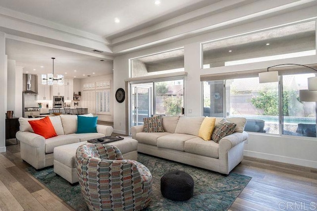 living room with hardwood / wood-style flooring, an inviting chandelier, and a healthy amount of sunlight