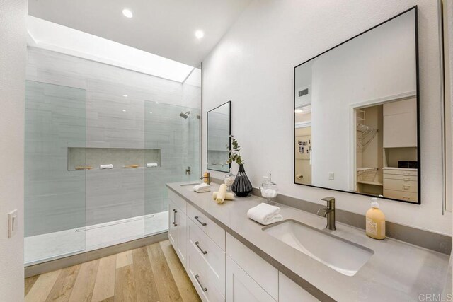 bathroom with a tile shower, vanity, hardwood / wood-style flooring, and a skylight