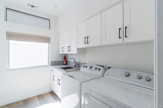 laundry area featuring washer and clothes dryer, light hardwood / wood-style floors, cabinets, and sink