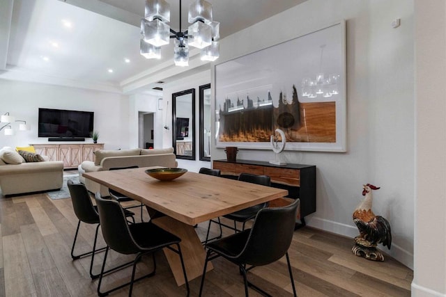 dining room with wood-type flooring, a tray ceiling, and a notable chandelier