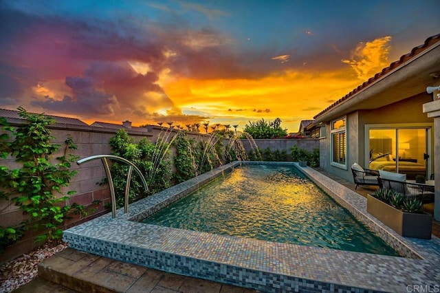 pool at dusk featuring a fenced in pool, a fenced backyard, and a patio