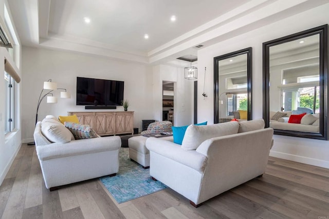 living room with recessed lighting, a raised ceiling, light wood-style flooring, and baseboards