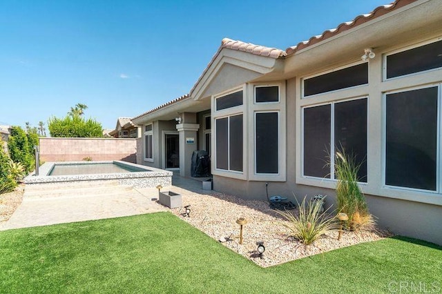 back of property featuring a tiled roof and stucco siding