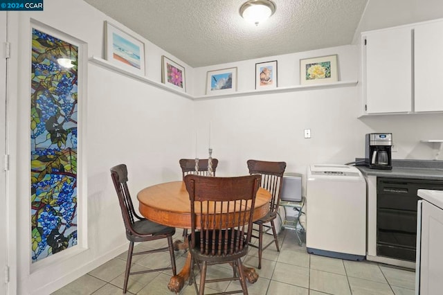 dining room featuring a textured ceiling, light tile patterned floors, and washer / dryer