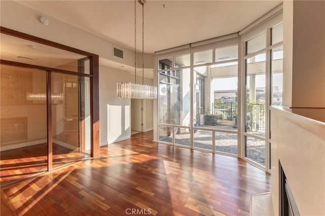 unfurnished dining area with floor to ceiling windows, hardwood / wood-style floors, and a notable chandelier