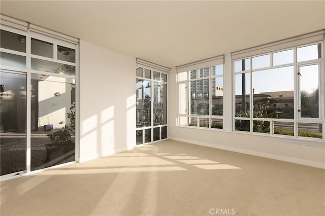 unfurnished sunroom with baseboards and carpet