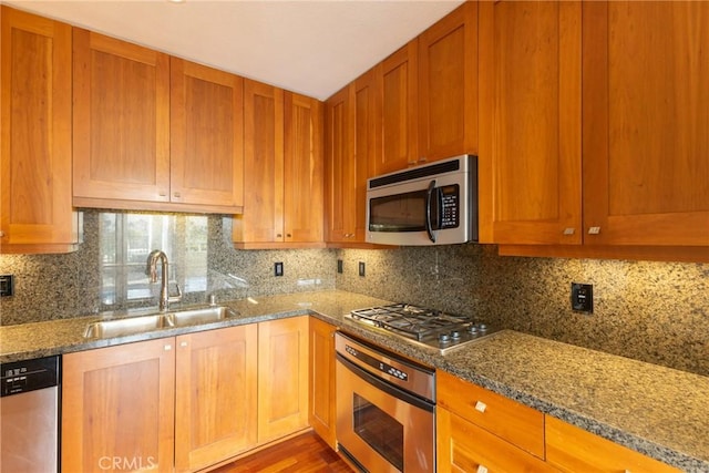 kitchen featuring stainless steel appliances, light stone countertops, and a sink