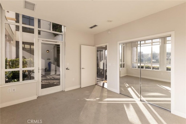 unfurnished bedroom featuring baseboards, access to outside, carpet, and visible vents