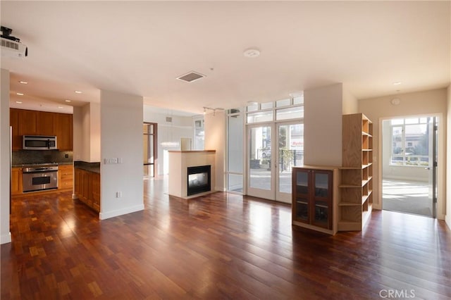 unfurnished living room featuring visible vents, recessed lighting, a multi sided fireplace, french doors, and dark wood finished floors