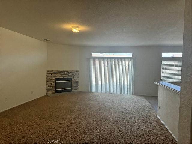 unfurnished living room featuring carpet flooring, a stone fireplace, and a textured ceiling