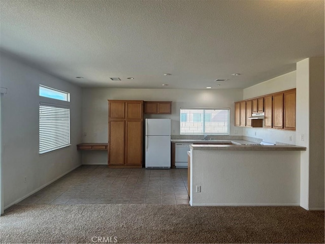 kitchen with sink, kitchen peninsula, light colored carpet, a textured ceiling, and white appliances