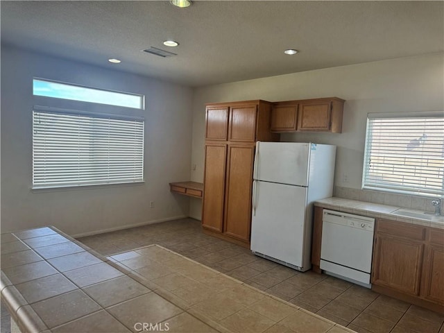 kitchen featuring light tile patterned floors, white appliances, tile counters, and sink