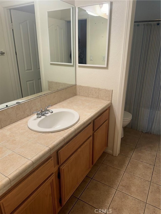 bathroom with toilet, vanity, and tile patterned floors