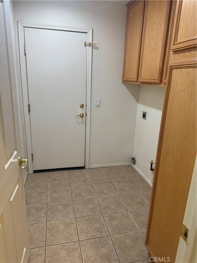 laundry area featuring hookup for an electric dryer, cabinets, and light tile patterned floors