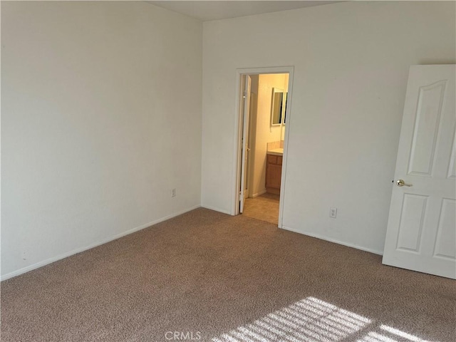 unfurnished bedroom featuring light carpet and connected bathroom