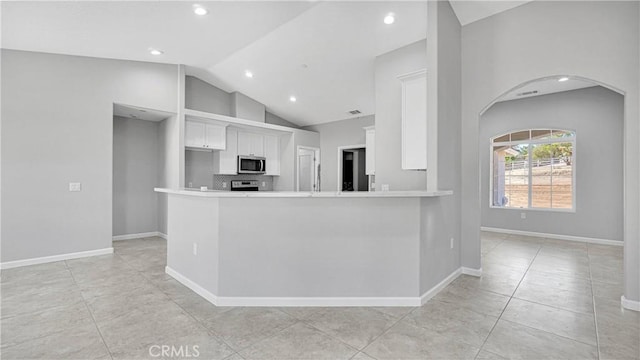 kitchen with kitchen peninsula, light tile patterned flooring, white cabinets, and stainless steel appliances