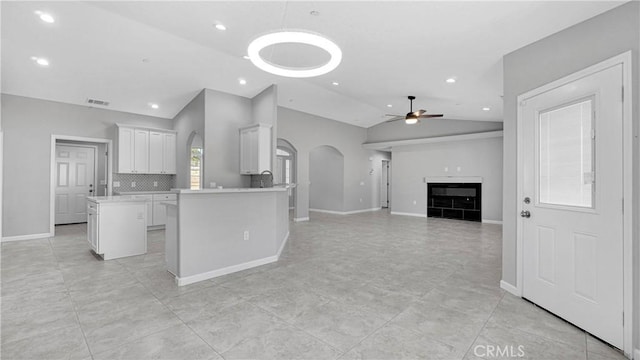 kitchen with a center island, lofted ceiling, white cabinets, ceiling fan, and kitchen peninsula