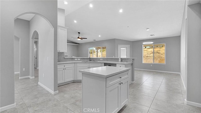 kitchen with a center island, backsplash, white cabinets, ceiling fan, and kitchen peninsula