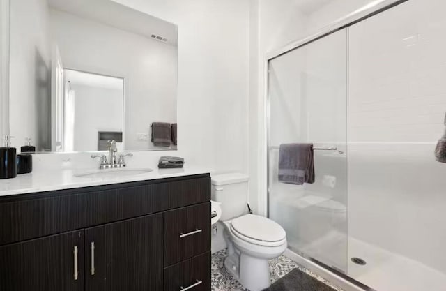 bathroom featuring tile patterned flooring, a shower with door, vanity, and toilet