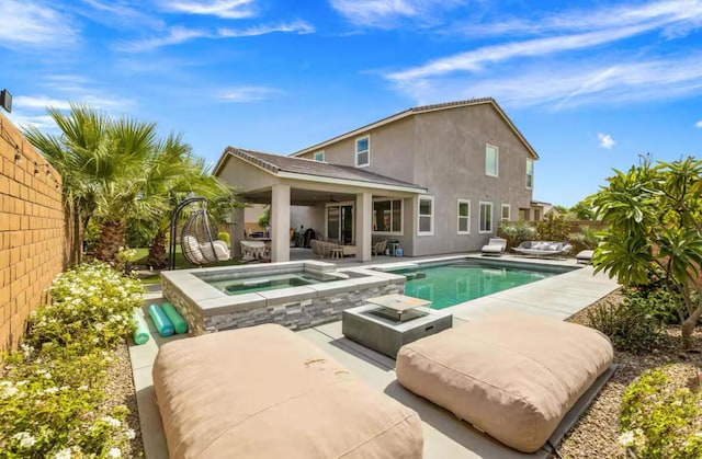 rear view of house with a patio area and a pool with hot tub