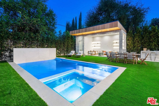 view of pool featuring an in ground hot tub, an outdoor structure, and a lawn