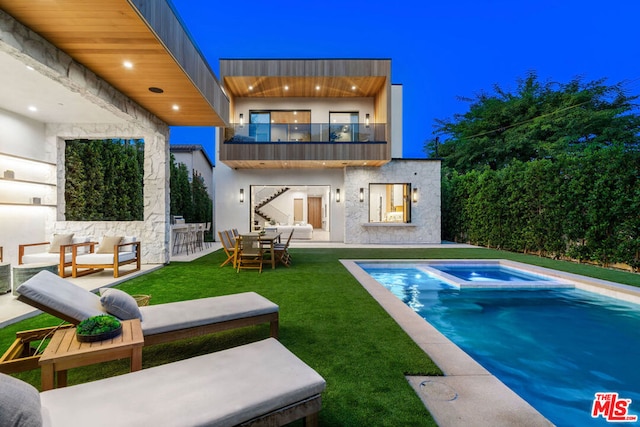 rear view of house featuring a balcony, a patio, a pool with hot tub, and a yard