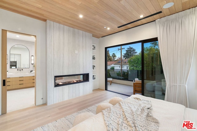 bedroom with access to outside, a fireplace, wooden ceiling, light hardwood / wood-style floors, and connected bathroom