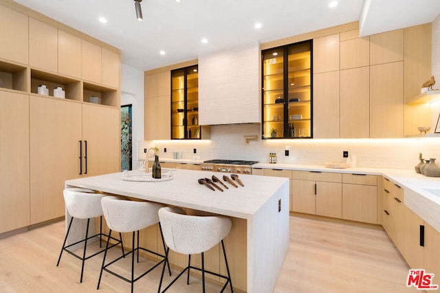 kitchen with a kitchen island, light wood-type flooring, tasteful backsplash, and light brown cabinetry