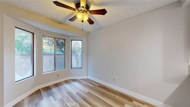 spare room with a textured ceiling, light wood-type flooring, and ceiling fan