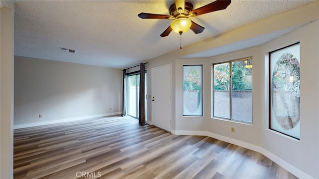 empty room featuring ceiling fan, a textured ceiling, and light wood-type flooring