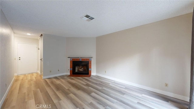 unfurnished living room featuring light hardwood / wood-style floors and a textured ceiling