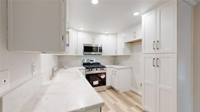 kitchen featuring sink, white cabinets, stainless steel appliances, and light hardwood / wood-style flooring