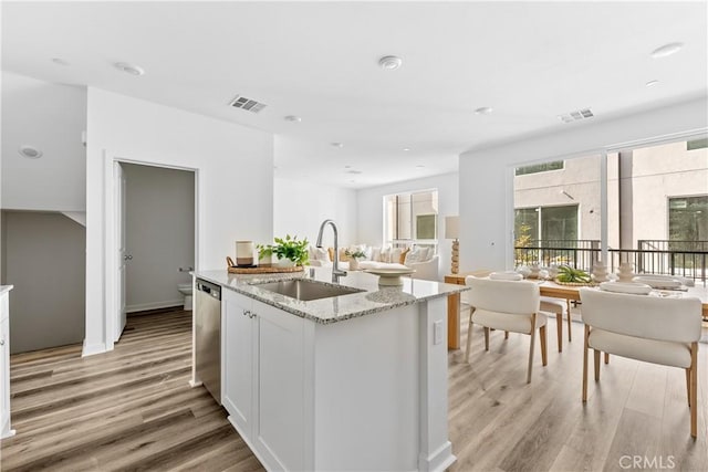 kitchen featuring light hardwood / wood-style floors, white cabinetry, stainless steel dishwasher, and sink