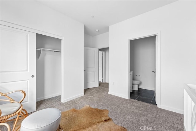 bedroom featuring ensuite bathroom, a closet, and dark carpet