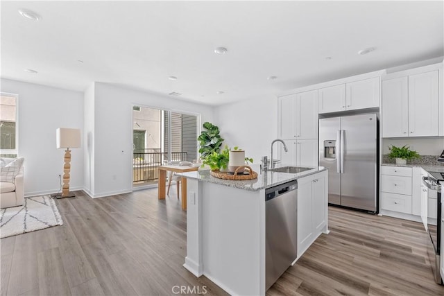 kitchen with sink, white cabinetry, stainless steel appliances, and light hardwood / wood-style flooring