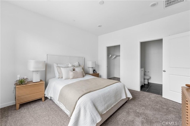 bedroom featuring dark colored carpet, ensuite bathroom, a spacious closet, and a closet