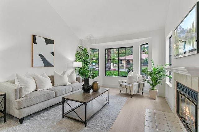 living room featuring a fireplace, lofted ceiling, and light wood-type flooring