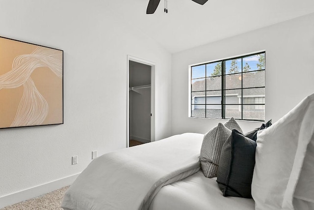 carpeted bedroom with ceiling fan, a closet, a spacious closet, and vaulted ceiling