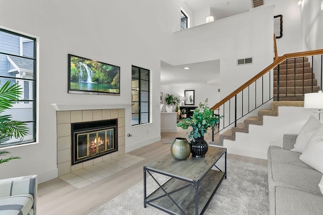 living room with a fireplace, a high ceiling, and light wood-type flooring