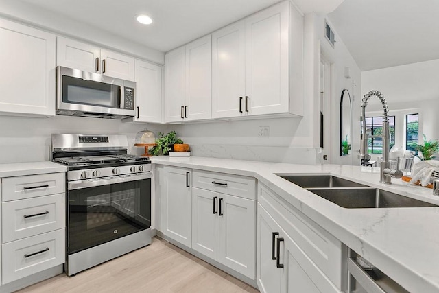 kitchen with white cabinets, sink, light wood-type flooring, and stainless steel appliances