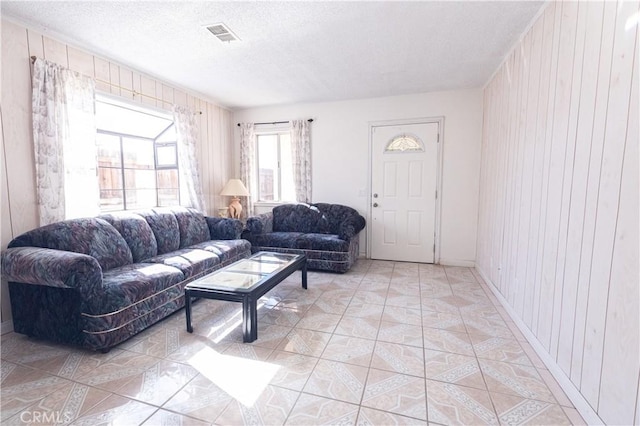 tiled living room with a textured ceiling and wood walls