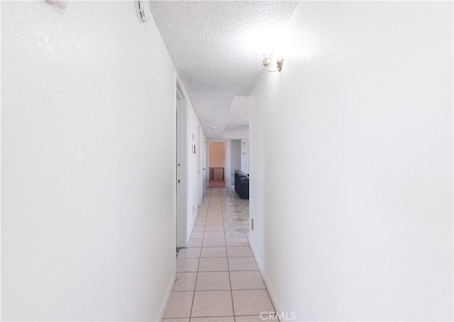 hallway with light tile patterned floors and a textured ceiling