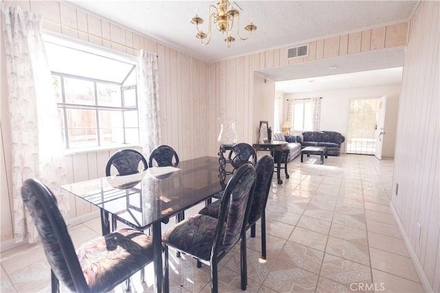 dining area with a wealth of natural light, light tile patterned floors, and a notable chandelier