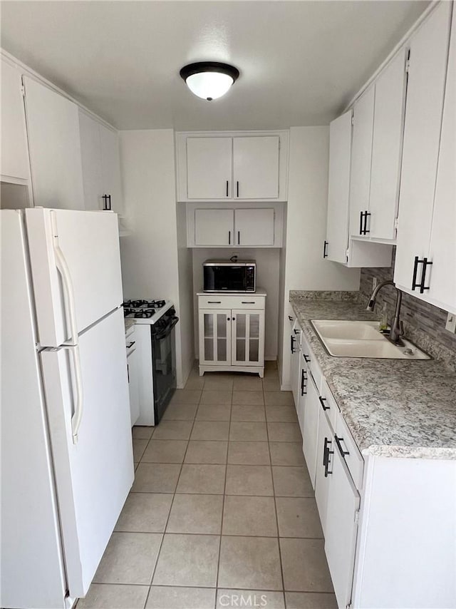 kitchen with light tile patterned flooring, white appliances, white cabinetry, and sink