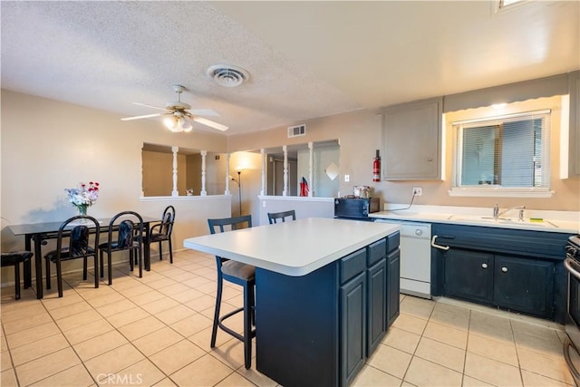 kitchen featuring white dishwasher, blue cabinets, a kitchen island, a breakfast bar, and sink