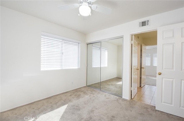 unfurnished bedroom with light colored carpet, a closet, and ceiling fan