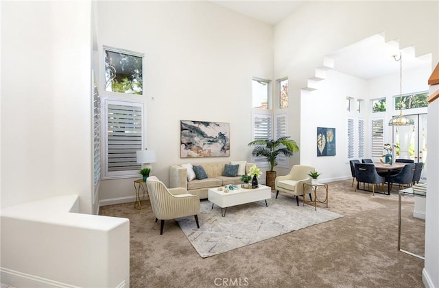 interior space with a high ceiling, carpet floors, a wealth of natural light, and a notable chandelier