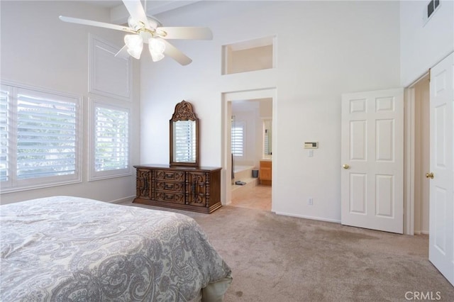 bedroom featuring a high ceiling, light colored carpet, and ceiling fan