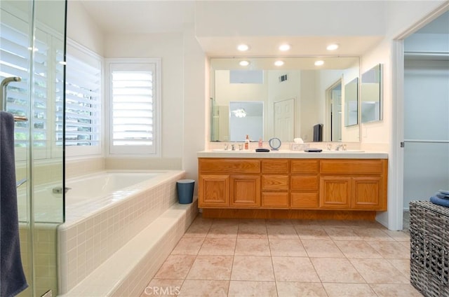 bathroom with tile patterned flooring, vanity, and tiled tub