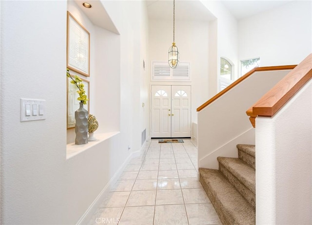 entrance foyer featuring light tile patterned floors and a towering ceiling